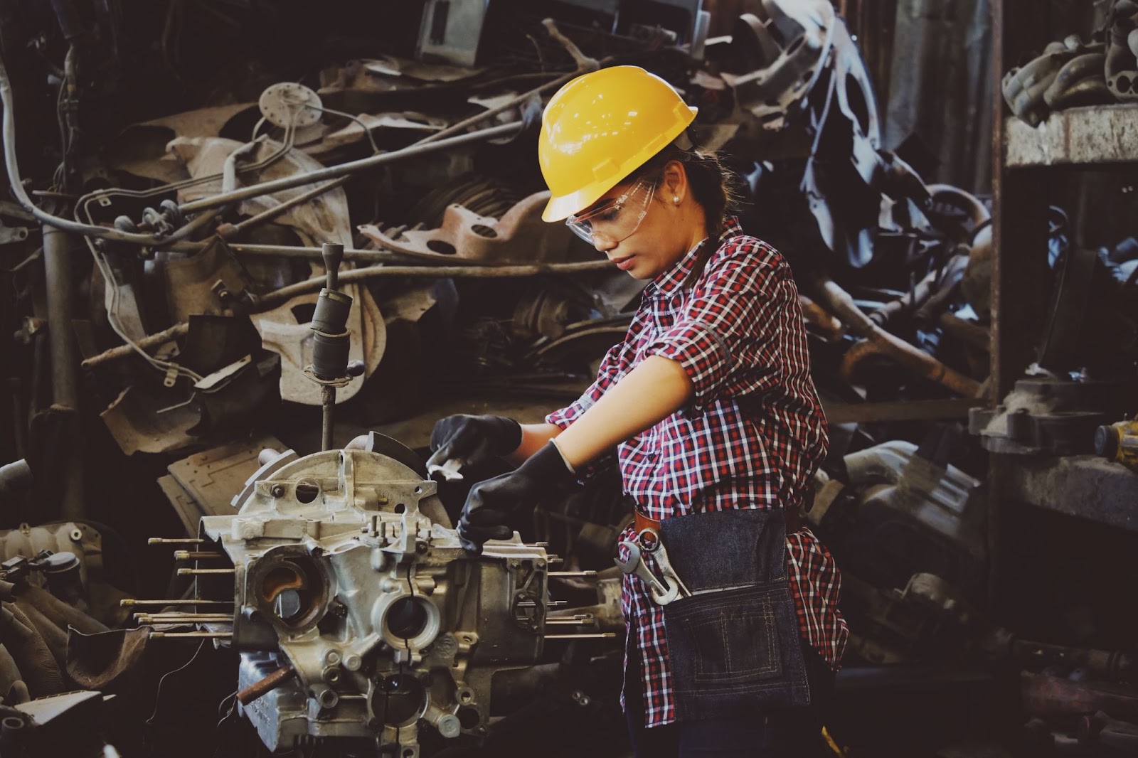 Mechanic wearing clear plastic glasses and a yellow hardhat