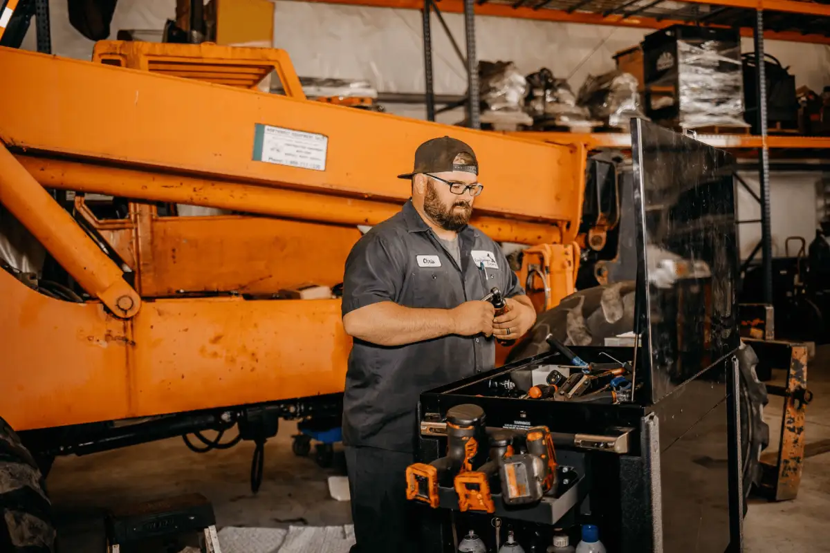 Mechanic performing maintenance on heavy equipment using a power tool