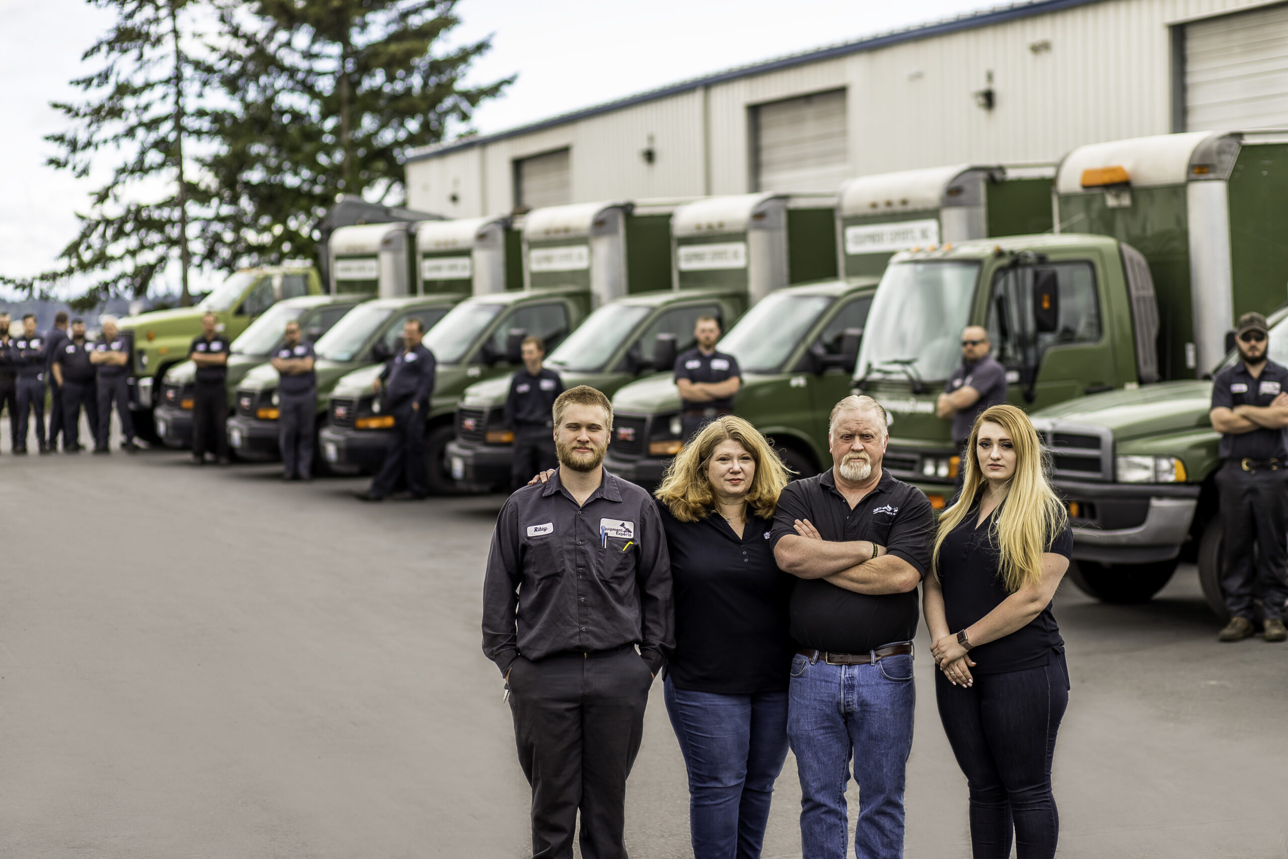 Equipment Experts, Inc. management fleet team with a fleet of truck drivers leaning against trucks in the background