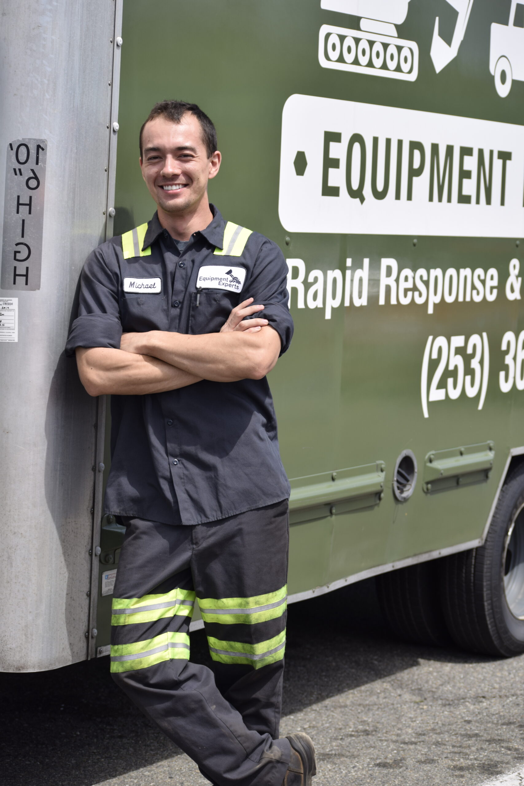 A smiling sales technician with his arms folded in front of the Equipment Experts, Inc. logo