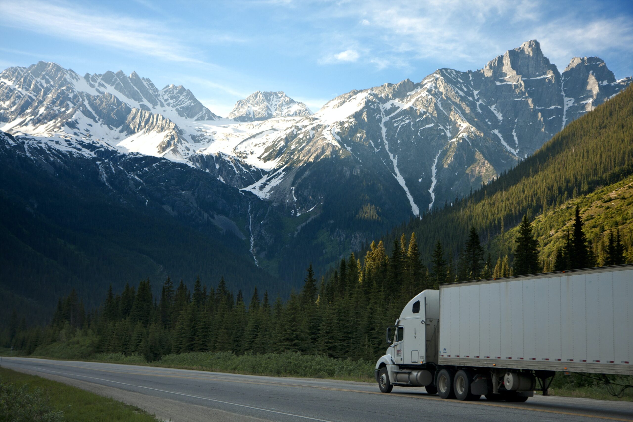 A truck on a highway against a backdrop of mountains