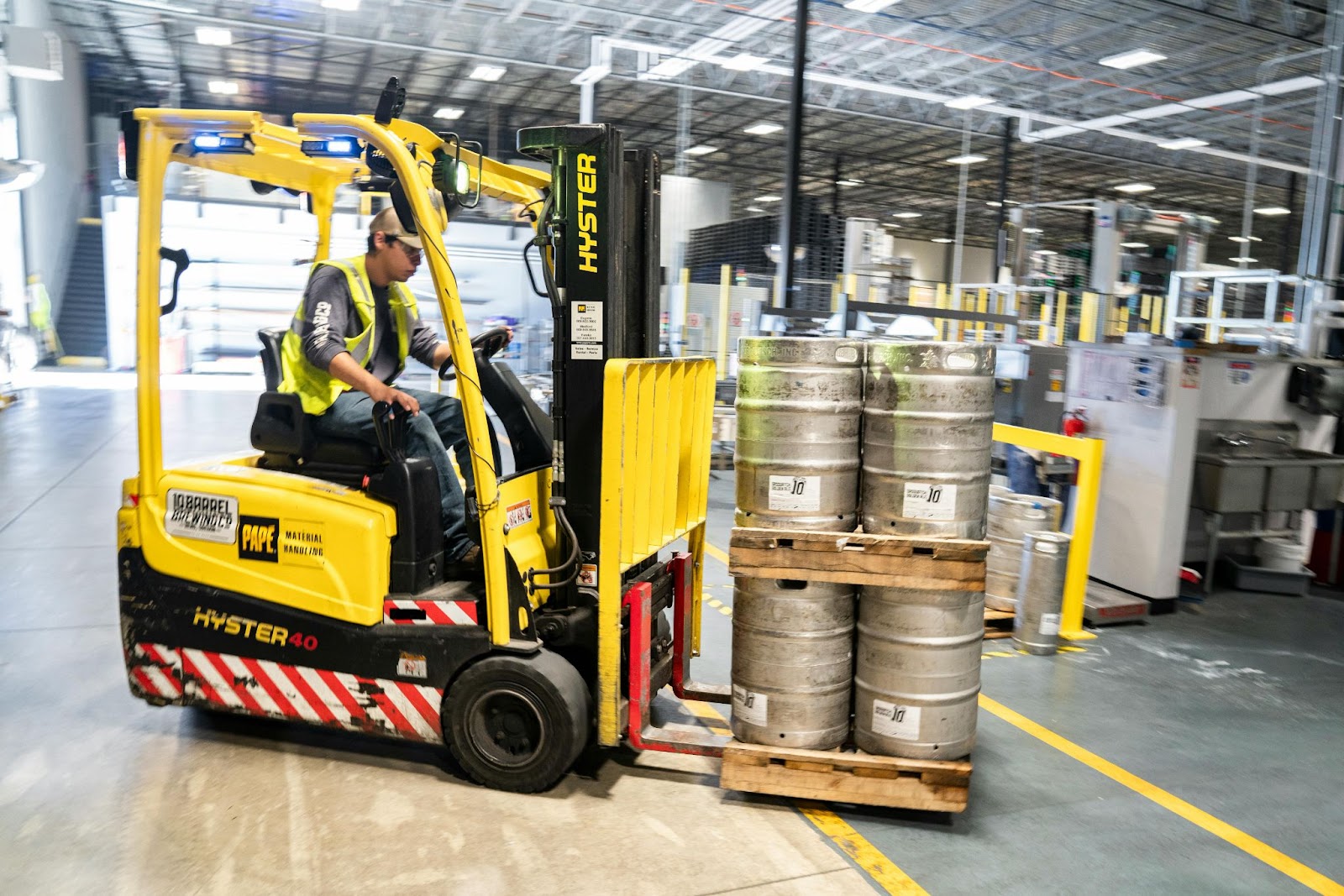 A class II forklift lifting steel drums in a warehouse
