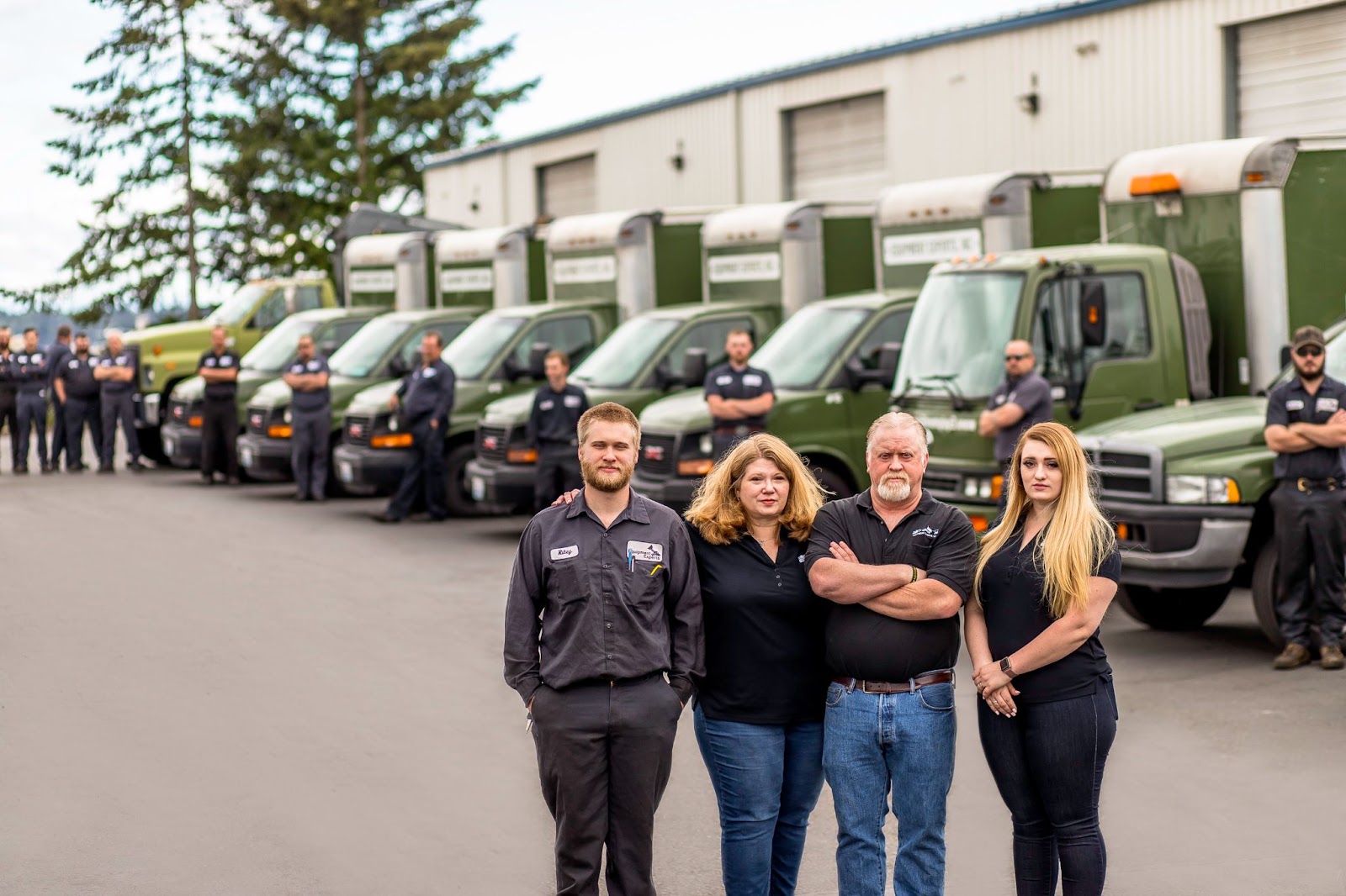 The Equipment Experts, Inc. staff in the foreground with their forklift technicians in the background lined up in a row against fleet vehicles