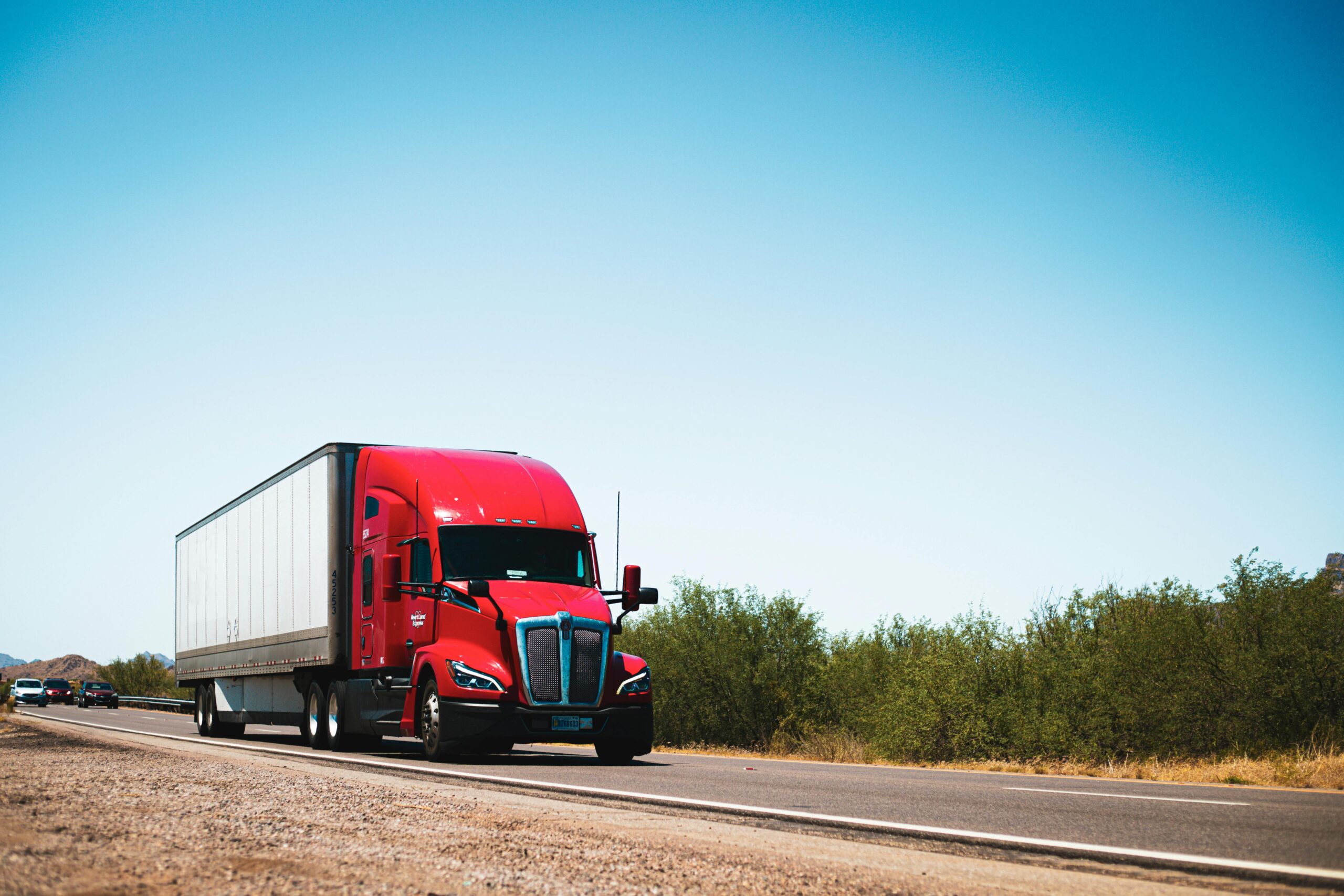 A picture of a red freightliner semi truck on a road