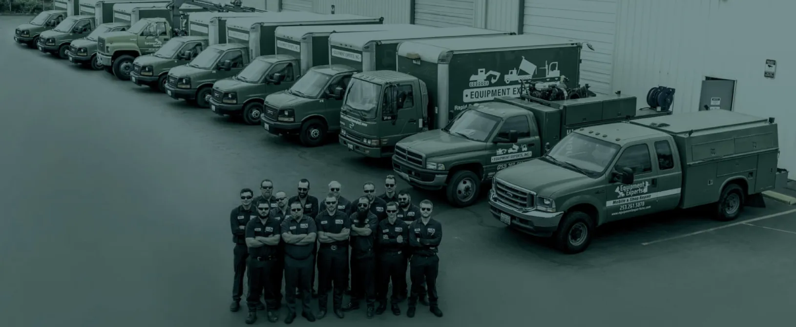 Aerial shot of the Equipment Experts team posing with their fleet of green service trucks outside the company facility