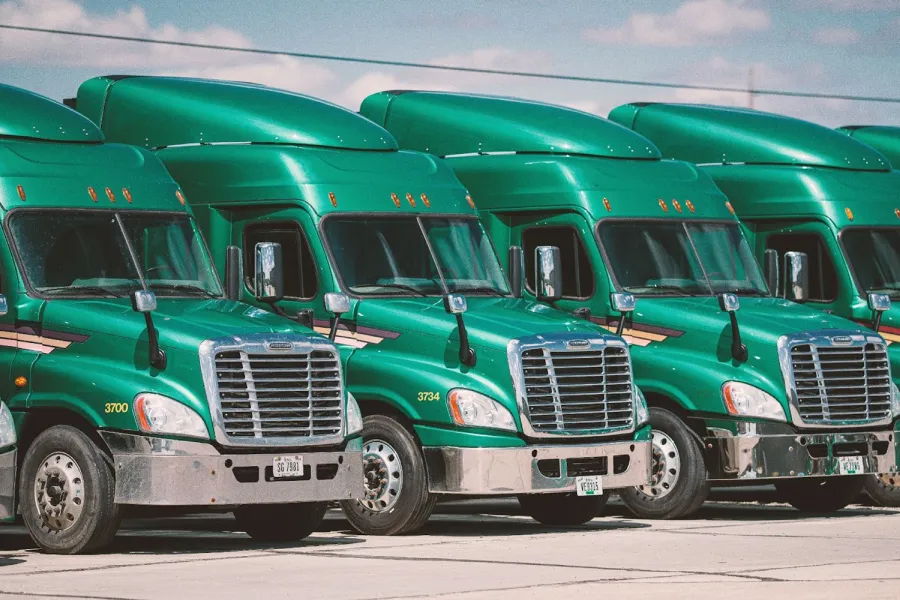Row of green semi-trucks parked in a lot