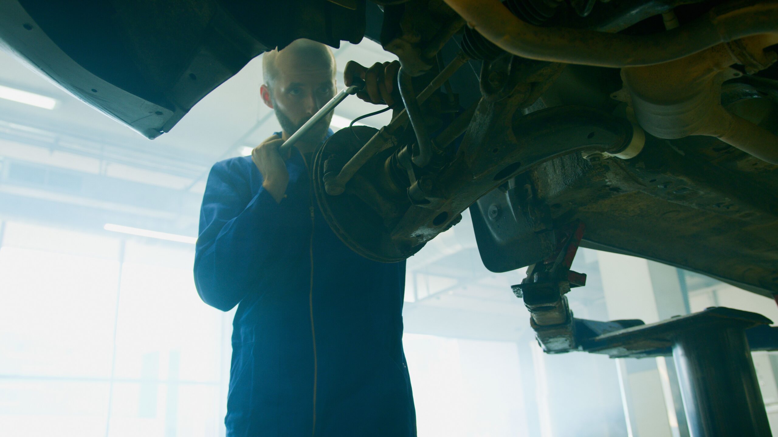 A person using a wrench to adjust a slack adjuster on a vehicle