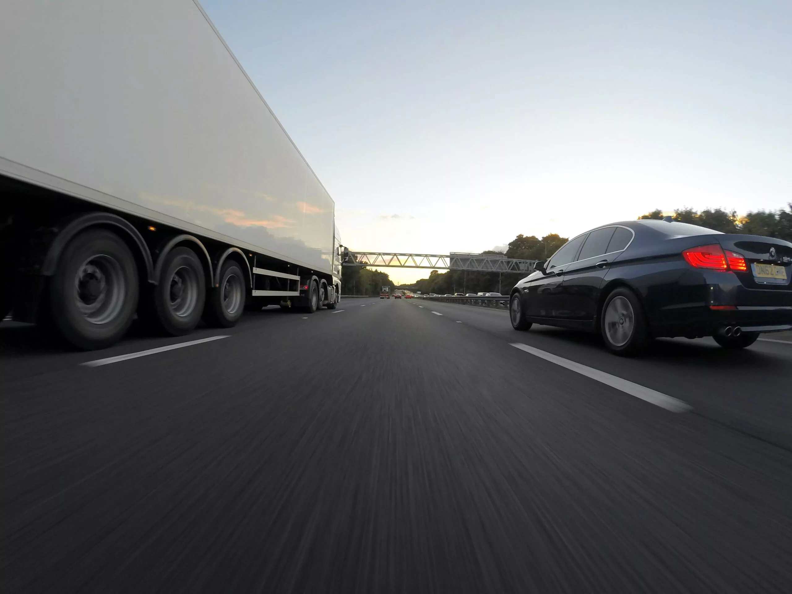 A sedan next to a semi-truck on a highway